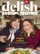 Delish Quarterly magazine cover featuring two smiling women enjoying a festive meal together with Cooking Together headline and dinner with friends feature