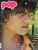 Pop Magazine cover featuring a close up portrait of Noor with curly hair wearing a striped top and scarf against a green background with 700 pages text