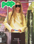 Pop Magazine cover featuring Rebecca in a yellow sweater and dark sunglasses at a magazine stand with colorful printed magazines nearby