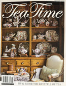 Tea Times Magazine cover featuring an elegant display of vintage teapots teacups and floral china in a wood cabinet beside a cozy armchair