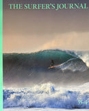The Surfer’s Journal Magazine cover featuring a surfer riding a powerful turquoise wave beneath a moody sky with foamy white surf
